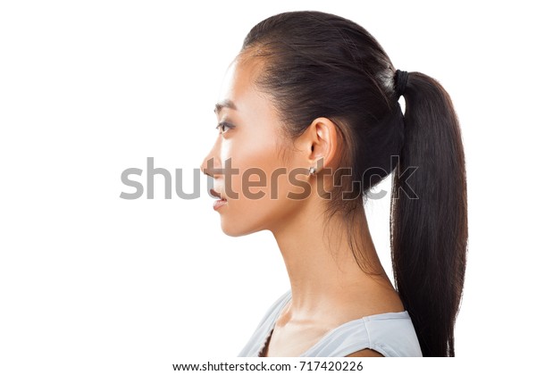 横顔にポニーテールのアジアの若い女性の接写 白い背景にさまざまな美容 医療プロジェクト用に 日に焼けた新鮮な肌と黒い髪を持つ美しい女の子のスタジオ写真 の写真素材 今すぐ編集