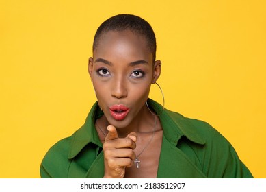 Close-up Portrait Of Assertive African American Young Woman With Shaved Head Pointing And Commanding While Looking At Camera Over Yellow Background