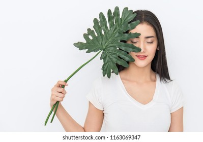 Closeup Portrait Of Attractive Asian Woman Has Green Leaf Cover Face With Perfect Healthy Glow Skin, Asian Beautiful Girl. Beauty Clinic Cosmetology Skincare Organic Green Natural Earth Day Concept