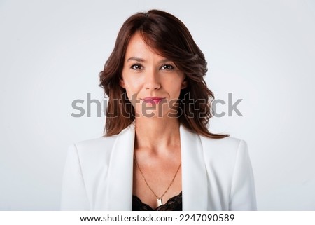 Close-up portrait of an attractive middle aged woman with toothy smile wearing blazer while standing at isolated dark background. Copy space. Studio shot.