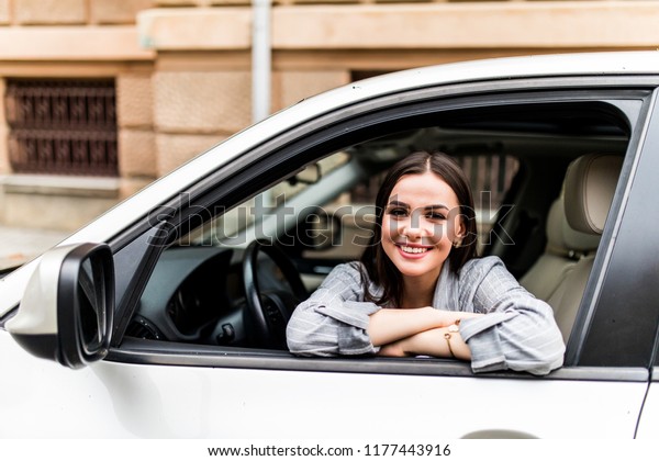 Closeup\
portrait attractive woman buyer sitting in her new car excited\
ready for trip isolated outside dealer dealership lot office.\
Personal transportation auto purchase\
concept
