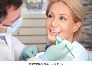 Close-up portrait of an attractive woman sitting at dentist office while male dentist checking her teeth. - Powered by Shutterstock