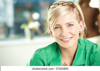 Closeup portrait of attractive young businesswoman wearing green shirt, smiling.
