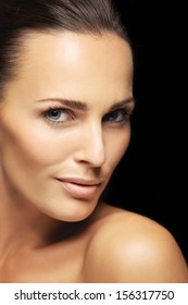 Close-up Portrait Of A Attractive Young Female With Flawless Skin Looking At Camera. Pretty Woman With Clean And Glowing Skin Isolated On Black Background