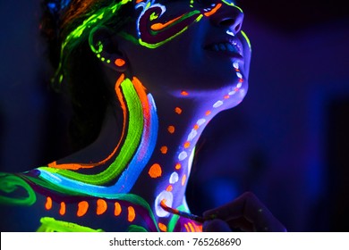 Close-up Portrait of an attractive young girl in bright blacklight bodyart