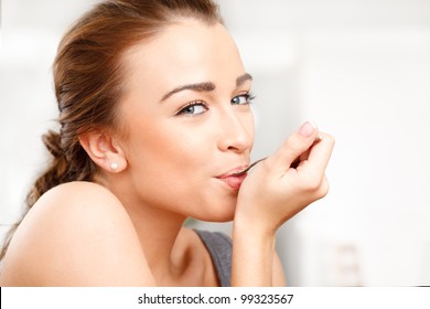 Close-up portrait of an attractive young woman eating yogurt - Powered by Shutterstock