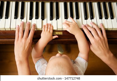 Closeup portrait of a baby learning to play piano with mother - from above - Powered by Shutterstock