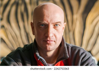 Close-up portrait of a bald man with blue eyes in a sports sweatshirt looks past the camera - Powered by Shutterstock