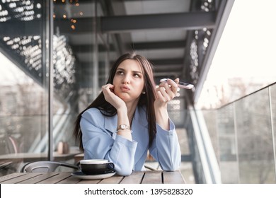 Closeup Portrait Of A Beautiful Annoyed Woman Holding Phone To Side, Not Listening To Conversation Girl Wearing Formal Blue Suit Sitting At A Table On Cafe Terrace Balcony Outside Staircase Background