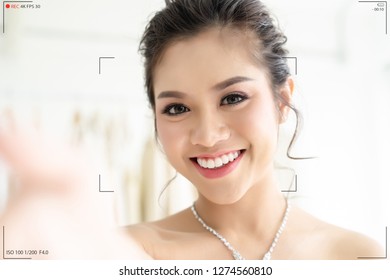 Closeup Portrait Of Beautiful Asian Woman In Elegant White Wedding Dress Make Selfie Recording Video Vlog From Hands With Mirrorless Camera In Wedding Atelier.Concept Vlog Live Streaming.