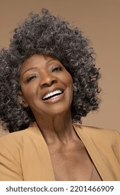 Close-up portrait of beautiful black woman of Brazilian decent in her 70s smiling confidently with an afro and looking gorgeous on neutral background Stock Photo
