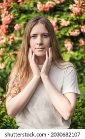 Close-up Portrait Of Beautiful Caucasian Woman With Long Blond Hair In The Park. Natural Beauty, Make Up Free. Pink Flowers On The Background. 