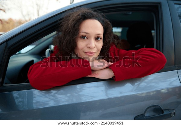 Close-up portrait of a beautiful confident African
American woman, female driver sitting on a driver seat and
confidently looking at
camera