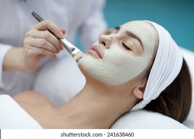 Close-up portrait of beautiful girl with a towel on her head applying facial mask