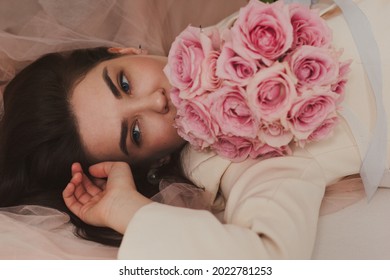 Closeup Portrait Of A Beautiful Happy Bride In Jacket On The Floor Holding A Rose Bouquet.