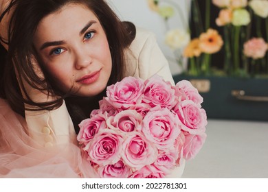 Closeup Portrait Of A Beautiful Happy Bride In Jacket On The Floor Holding A Rose Bouquet.