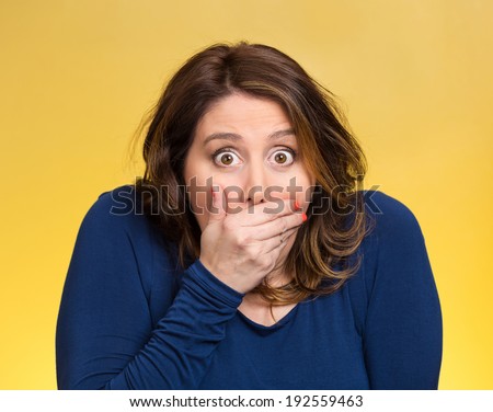 Closeup portrait beautiful, middle aged shocked young woman, covering her mouth, wide open eyes, isolated yellow background. Negative human emotion, facial expression, feeling, signs, symbol, reaction