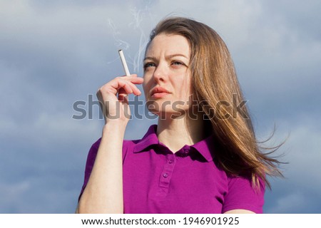 closeup portrait of beautiful pensive girl with cigarette on the background of the sky. smoking and unhealthy lifestyle concept