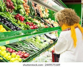 Closeup portrait, beautiful, pretty young woman in sweater picking up, choosing green leafy vegetables in grocery store - Powered by Shutterstock