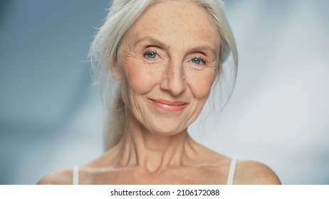 Close-up Portrait of Beautiful Senior Woman Looking at Camera and Smiling Wonderfully. Gorgeous Elderly Lady with Natural Lush Grey Hair, Blue Eyes. Beauty and Dignity of Old Age