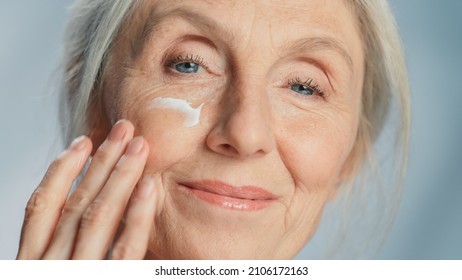 Close-up Portrait Of Beautiful Senior Woman Gently Applying Under Eye Face Cream. Elderly Lady Makes Her Skin Soft, Smooth, Wrinkle Free With Natural Anti-aging Cosmetics. Product For Beauty Skincare