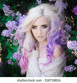 Close-up Portrait Of A Beautiful Sexy Young Blonde Girl Hipster With Lilac And Pink Hair On The Background Of Blooming Lilacs, Posing With Bright Makeup