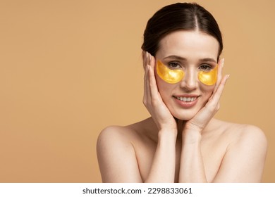 Closeup portrait of beautiful smiling caucasian woman using golden under eye patches looking at camera, isolated on beige background. Skin care, face mask, natural beauty concept - Powered by Shutterstock