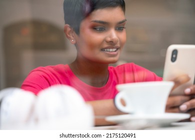 Closeup Portrait Of Beautiful Smiling Indian Woman Holding Mobile Phone Communication Online, Reading Text Message Sitting In Cafe. Happy Asian Female Using Mobile App Shopping Online. E-commerce