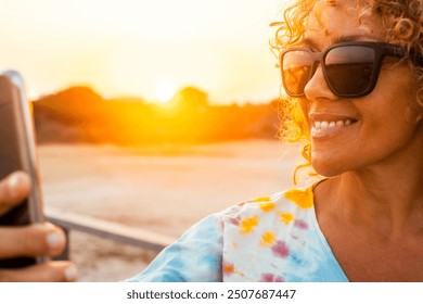 Close-up portrait of a beautiful, smiling woman with blonde curly hair, wearing stylish sunglasses, enjoying a sunny day outdoors while taking a selfie or video calling. Captures happiness and lifesty - Powered by Shutterstock