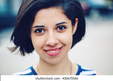 Closeup portrait of beautiful smiling young latin hispanic girl woman with short dark black hair bob, black eyes, outside looking in camera, toned with Instagram filters, natural smile emotion