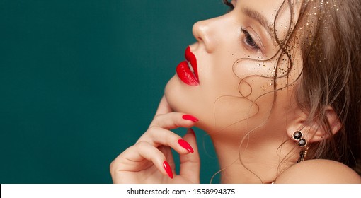 Close-up portrait of beautiful woman with holiday make-up. Perfect red lips and nail design. Gold glitters on her face. Christmas make-up - Shutterstock ID 1558994375