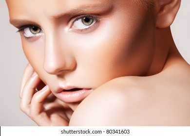 Close-up portrait of beautiful woman model with bronze make-up with bright glitter. Plastic surgery and tanned. Fashion frown model face, bronzer makeup