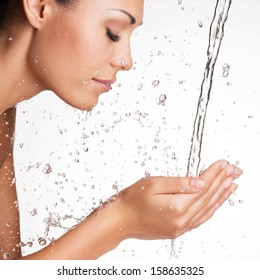 Closeup portrait of a beautiful woman washing her clean face with water  