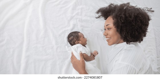 Closeup portrait of beautiful young African American mother day girl kiss healthy newborn baby sleep in bed flat lay copy space. Healthcare medical love black woman lifestyle mother's day, top view - Powered by Shutterstock