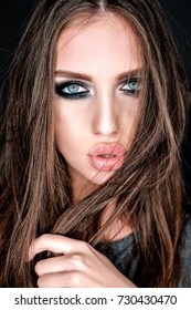 Close-up portrait of beautiful young  brown-haired woman with big sensual lips and languishing look touching her hair on dark background. Gorgeous glamour lady portrait