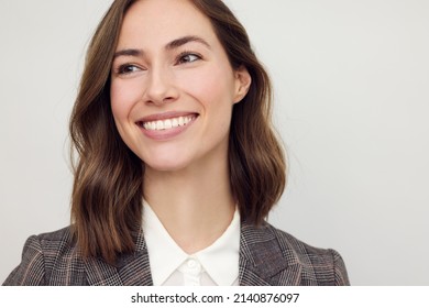 Close-up portrait of beautiful young businesswoman looking happy and confident to the left. Big smile on her face, looking beautiful and cheerful standing isolated on white background.