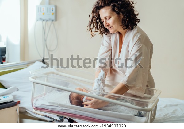 Closeup portrait of\
beautiful young caucasian mother calm down her newborn baby\
sleeping on hospital bed. Healthcare and medical family love\
lifestyle nursery mother day\
concept.