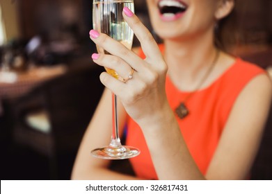 Close-up Portrait Of A Beautiful Young Elegant Sexy Blonde Woman In The Cafe With A Glass Of Champagne,White Wine  Smiling  And Drink Posing, With A Ring On Her Finger, She Is Engaged