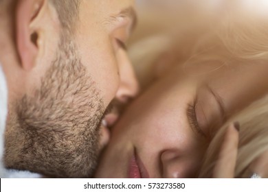 Close-up portrait of a beautiful young kissing couple in bed at home