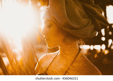 close-up portrait of a beautiful young sensual sexy woman with a turban on his head and African ornaments  full lips and expressive eyes on a sunny day at sunset in the tropical hot jungle in Thailand