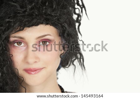 Close-up portrait of beautiful young woman with teased hair over gray background