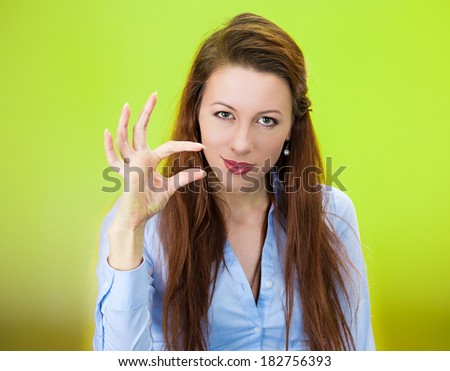 Closeup portrait of beautiful young woman showing small amount gesture with hands, isolated on green background. Negative human emotion facial expression feelings, body language, signs, symbols.