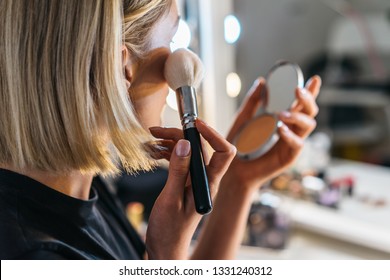 closeup portrait of blond woman who do make up with brush and powder in a room with professional lights. pretty middle age female make up one's face
 - Powered by Shutterstock