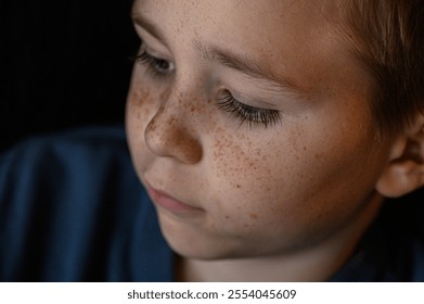 Close-up portrait of a boy with large blue eyes, long dark eyelashes, and a face full of freckles - Powered by Shutterstock