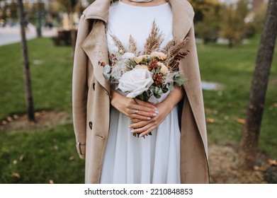 Close-up portrait of a bride in a white dress, beige coat with a bouquet of wildflowers. wedding photography. - Powered by Shutterstock