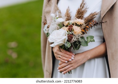 Close-up portrait of a bride in a white dress, beige coat with a bouquet of wildflowers. wedding photography. - Powered by Shutterstock