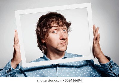 Closeup portrait businessman executive looking at camera, curious surprised confused through white picture frame thinking beyond borders accepted rules isolated grey background.Face expression emotion - Powered by Shutterstock