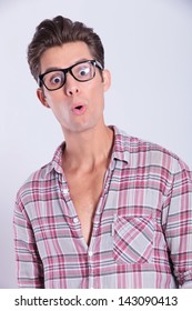 Closeup Portrait Of A Casual Young Man Looking With Surprise At The Camera. On Gray Background