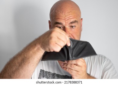 Close-up, Portrait Caucasian Adult Man, With A Sweaty Face, Seriously Looks At The Empty And Penniless Wallet.