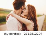 Close-up portrait of a caucasian young loving couple embracing while standing on a roadside. Couple embracing road travel. Sunset scene.